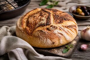 Goldbraunes Grillbrot frisch vom Rost, mit Kräuterbutter und frischen Kräutern auf einem Holzbrett